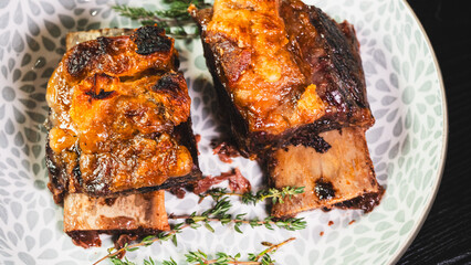 Tender, fall-off-the-bone braised beef short ribs, presented on a plate with fresh thyme. A rich, hearty, and deeply flavorful main course, perfect for comfort food imagery.