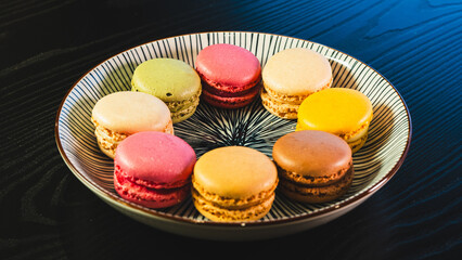 A beautiful assortment of vibrant and colorful French macarons, elegantly presented on a white plate. Perfect for dessert tables, pastry shop promotions, and food blog imagery.