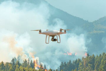 Firefighting drones. Unmanned aerial vehicles designed to assist firefighters in fighting fires. A drone raised above a burning forest in the daytime