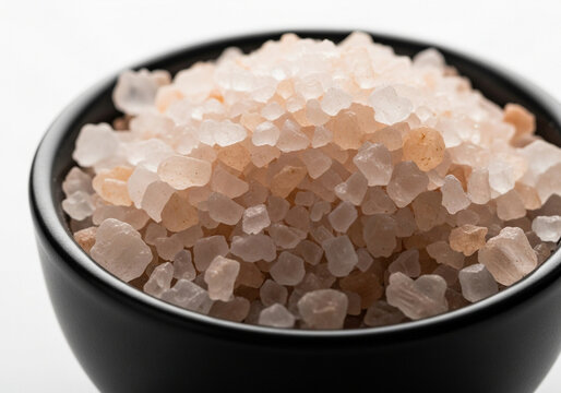 Closeup of pink himalayan salt crystals in a black bowl isolated on white background - Powered by Adobe