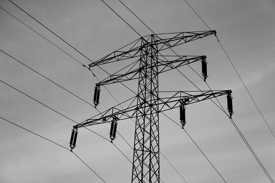 High-Voltage Power Line Tower Against a Cloudy Sky Infrastructure and Energy Distribution