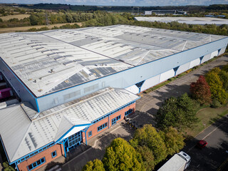 Aerial drone view of expansive modern warehouse with curved roof and multiple loading docks...