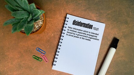 Dictionary definition of "Disinformation" written on a spiral notebook.