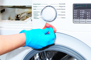 Woman hand in rubber glove cleaning washing machine with sponge