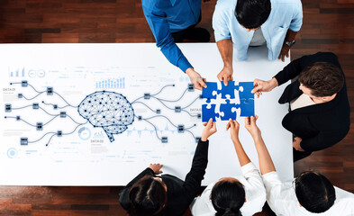 Team members collaboratively solve a puzzle over a table featuring a brain graphic and data visualization, highlighting the importance of teamwork in strategic innovation sessions. Trope