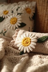 Delicate crocheted daisy flowers adorn a beige knitted blanket and pillows, showcasing a soft and cozy aesthetic.