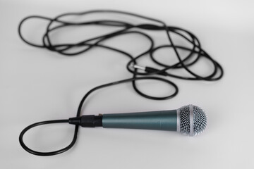 Close-up view of a microphone with tangled cable on a plain background, showing details of design and texture in a well-lit setting