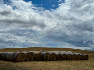 Closeup of some hay bales lying on a Tuscan hill. Landscape of Tuscan countryside in Val d'Orcia and so called crete senesi. Cloudy day in Tuscany.