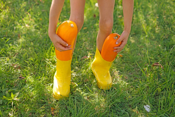 Close-up of two large ripe squash vegetables in yellow children's rain boots. Autumn harvest season