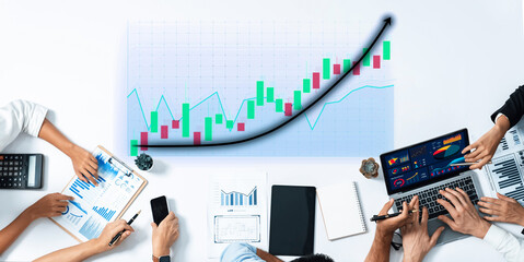 A professional business team collaborates on financial charts and graphs, using technology to...