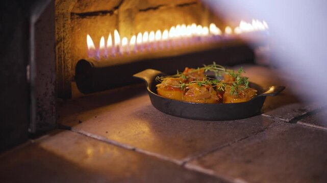 Culinary Delight: A close-up shot of a gourmet dish, beautifully presented in a rustic, cast-iron skillet, being baked to perfection, illuminated by the warm, flickering flames of a traditional oven.