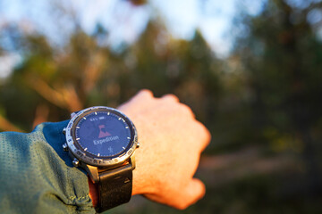 Person Check Hiking Watch in Forest Late Afternoon, Capturing Essence of Outdoor Adventures. Expedition Adventure, Hiking Watch on Forest Background. Adventure Watch Displayed on Wrist in Forest.