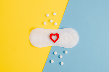 Women's sanitary pads with a red heart and pills on a yellow-blue background.