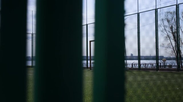 Pan shot of metal goal placed on football pitch covered with green lawn