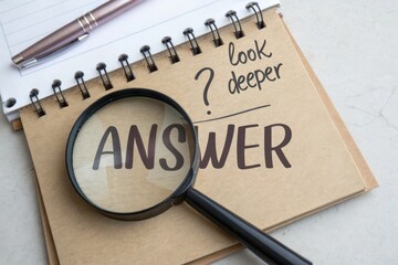Magnifying glass highlighting answer text on notebook with pen beside