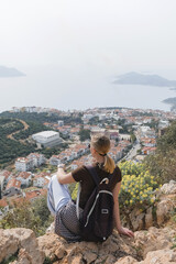 Young woman relaxing barefoot on rocky summit above coastal bays, embraces mindfulness and digital detox. Slow travel, wellness retreat energy—freedom, stillness and panoramic escape inspire balance.