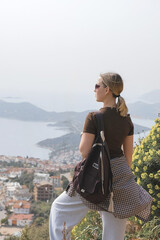 Young woman relaxing barefoot on rocky summit above coastal bays, embraces mindfulness and digital detox. Slow travel, wellness retreat energy—freedom, stillness and panoramic escape inspire balance.