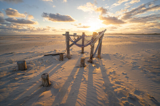 Sonnenuntergang am Strand von Amrum mit einer H&auml;ngematte im Vordergrund aus Fischnetze