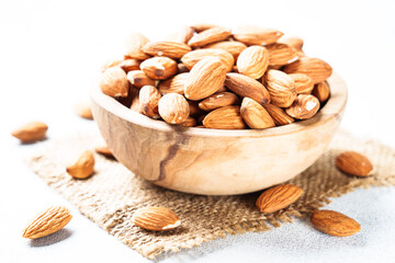 Almond nuts in wooden bowl at white background.