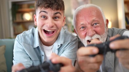 Cheerful grandson and grandfather playing video games together at home - Powered by Adobe