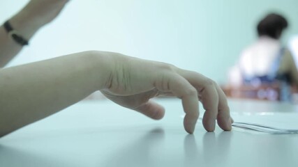 Close-up of a nervous hand with a golden ring, tapping and fidgeting on a desk next to a stack of papers. Stress and anxiety at work. - Powered by Adobe
