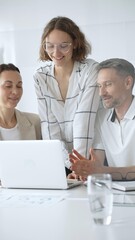 Obraz premium Professional team reviewing project data on laptop, working together in modern office environment, collaborating with focused corporate energy