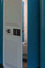 Portable toilet cabin with open door, showing the interior. Concept of outdoor sanitation, hygiene, and temporary facilities for public events or construction sites.