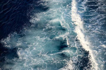 Vue aérienne des vagues de l'océan créant un motif texturé dans l'eau bleue au large de la côte
