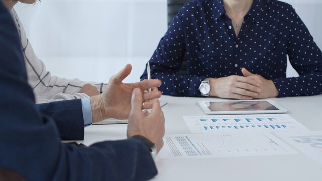 Business people examining and discussing financial documents, studying performance charts on paper and digital tablet during collaborative meeting in modern office - Powered by Adobe