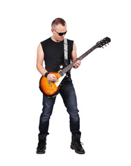 A man in jeans and a T-shirt wearing dark glasses plays an electric guitar