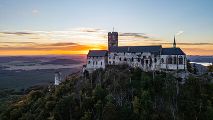 Bezdez Castle, a medieval ruin perched on a hill, offers a stunning aerial view as the sun sets in...