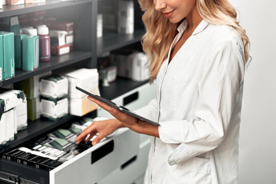 Pharmacist using tablet for medicine inventory in pharmacy - Powered by Adobe