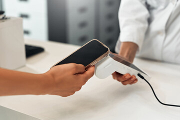 Contactless payment with smartphone at modern pharmacy checkout counter