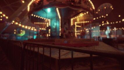 An amusement park lies quiet and still at night, featuring an empty carousel surrounded by glowing lights. The atmosphere feels eerie yet nostalgic, lacking the usual sounds of laughter and joy. © icetray