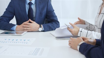 Business team engaging in a corporate meeting, discussing strategies while analyzing financial charts and graphs on a digital tablet alongside printed documents