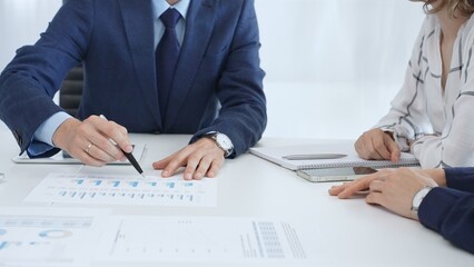Business team engaging in a corporate meeting, discussing strategies while analyzing financial charts and graphs on a digital tablet alongside printed documents