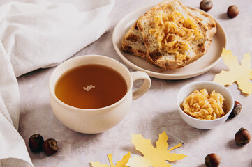 A cup of tea and autumn toast with apple jam on a plate on the table
