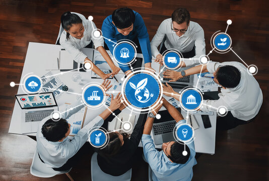 A diverse team collaborates in a business meeting, focusing on sustainability and innovation, with hands reaching across laptops and a globe symbolizing global impact. Amity