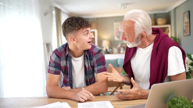 Grandfather helping grandson celebrating successful agreement at home