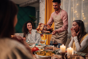Chef showing roasted turkey to friends at thanksgiving dinner