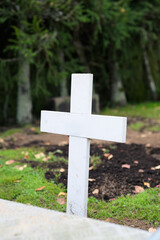 White cross in the cemetery, closeup of photo with shallow depth of field