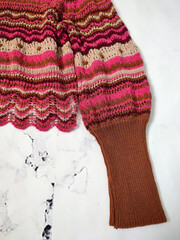 Pink brown striped openwork crochet sweater top. Long sleeve with wide ribbed cuff close up. Clothes details, jersey, knitwear, wave pattern, boho style 