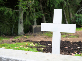 White cross in the cemetery, closeup of photo with shallow depth of field