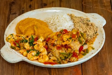 Brazilian moqueca capixaba is a typical dish from Espírito Santo, Brazil, with sea fish and shrimp, cooked in a clay pot and accompanied by white rice, pirão and farofa.