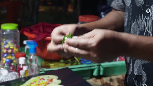 A person preparing paan,Paan is made from a betel leaf and  variety of ingredients, including areca nut, slaked lime, and various spices and sweeteners 