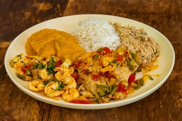 Brazilian moqueca capixaba is a typical dish from Espírito Santo, Brazil, with sea fish and shrimp, cooked in a clay pot and accompanied by white rice, pirão and farofa.