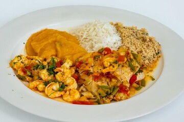 Brazilian moqueca capixaba is a typical dish from Espírito Santo, Brazil, with sea fish and shrimp, cooked in a clay pot and accompanied by white rice, pirão and farofa.