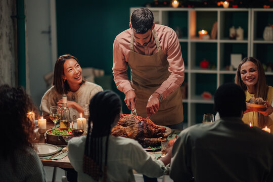 Chef carving turkey for friends at christmas or thanksgiving dinner