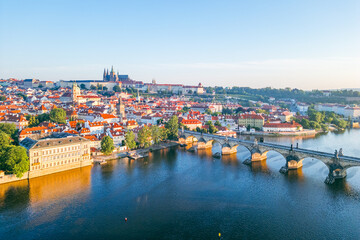 A breathtaking sunrise illuminates the medieval architecture of Prague, casting a warm glow over the Vltava River and the iconic Charles Bridge, showcasing the city's beauty at dawn.