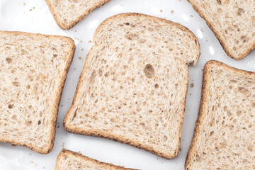 Slices of wholemeal bread on a white plate. Healthy bakery product rich in fiber, ideal for toast, breakfast, and balanced diets.
